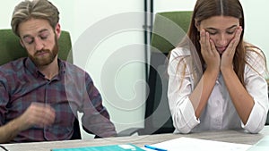 Man and woman work in modern office sitting at the table close up. People are sleepy and tired