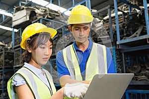 Man and woman work together, diversity of Asian engineer workers stand and seriously using laptop in factory-warehouse