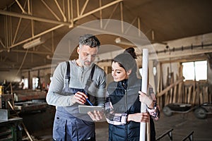 Man and woman workers with tablet in the carpentry workshop.