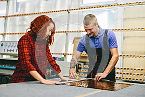 Man and woman working on glass pane in glazier workshop