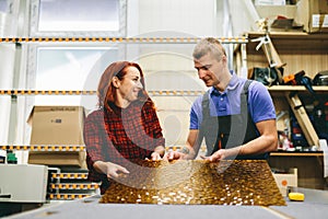 Man and woman working on glass pane in glazier workshop