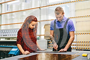 Man and woman working on glass pane in glazier workshop