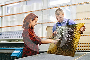 Man and woman working on glass pane in glazier workshop