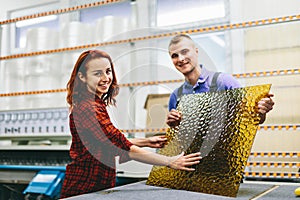 Man and woman working on glass pane in glazier workshop