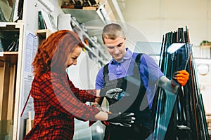 Man and woman working on glass pane in glazier workshop