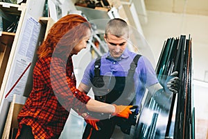 Man and woman working on glass pane in glazier workshop