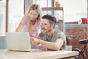 Man and woman working on laptop in office