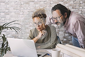 Man and woman working together on laptop in home office at the table desk. People and online digital job business. Adult couple