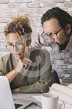 Man and woman working together on laptop in home office at the table desk. People and online digital job business. Adult couple