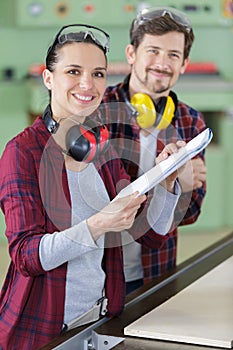 man and woman in workshop holding instructions for machinery