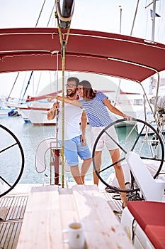 Man and woman on yacht at wheel going on ocean trip. Summer holiday