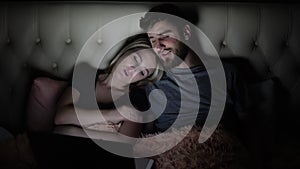 Man and woman, young couple watching boring movie on laptop in bed before bedtime