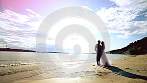 Man and woman, young happy married couple silhoutte kissing on the shore.