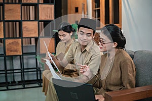 man and women civil servants holding and looking paperwork when sitting while working online