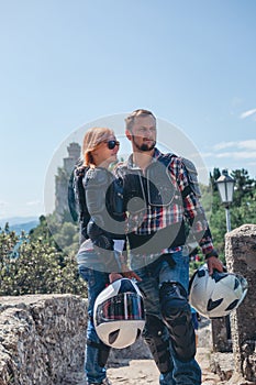 Man and woman couple. Dressed in a motorcycle outfit and sunglasses. body protection turtle and knee pads, helmet in hand. photo