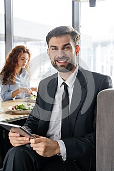 Businesspeople having business lunch at restaurant sitting man close-up holding digital tablet looking camera smiling