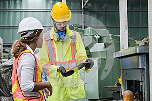 Man and women Industrial engineers wearing safety uniform and hard hats with tablet working heavy industry.