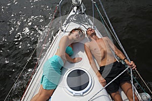 Man and woman lie on snout of yacht on river at photo