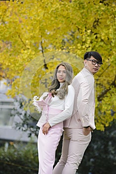 Man and woman in love stand together under autumn trees