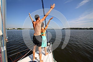 Man and woman pose as birds on snout of yacht on photo