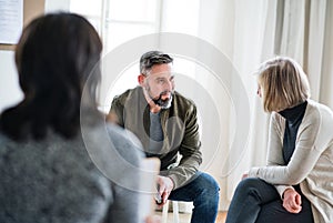 Man and women sitting in a circle during group therapy, talking.