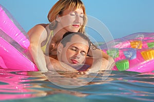 Man and women sleep on an mattress in pool