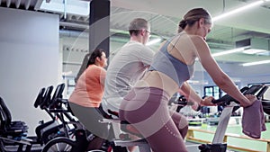 Man and women spinning on fitness bikes in the gym