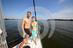 Man and woman stand together on snout of yacht on photo