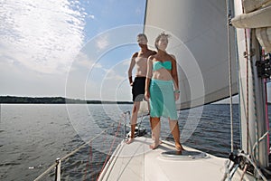 Man and woman stands on snout of white yacht on photo