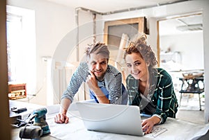 Young couple with laptop in the carpenter workroom.