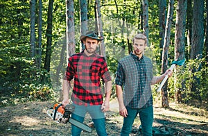 Man woodcutter holding ax. Axe in lumberjack hands cutting wood. Lumberman with a chainsaw in forest. Concept of a