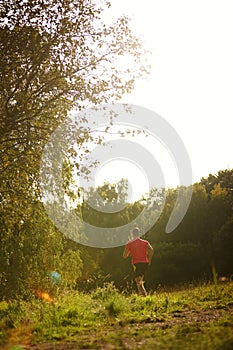 Man, woods and trail running outdoors with athlete for endurance with training for physical fitness. Male person, back