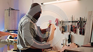 Man in woodworking shop inspecting lumber piece before assembling furniture