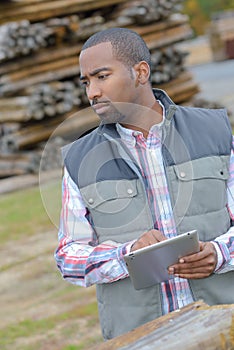 Man in woodyard with tablet computer