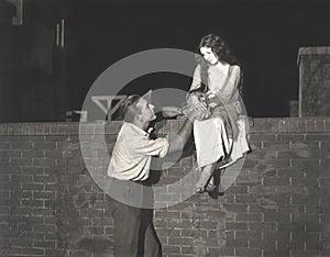 Man wooing woman sitting on brick wall