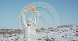 Man wore in protective suit raise stop plastic sign on abandoned place in winter