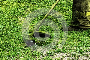 Man in work clothes mows green grass with a trimmer