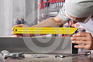 Man work in home workshop garage measure metal with ruler angle square, on the workbench with wrenches and hammer, diy and craft