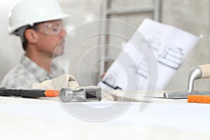 Man work, professional construction worker looking at blueprints on interior building site, wear safety hard hat and protective