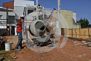 Man, construction worker using cement mixer, Brazil, south America , panoramic photo, selective focus, pouring cement