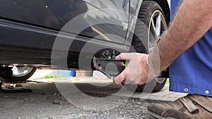 A man in work trousers replaces a car wheel,Slow Motion