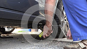 A man in work trousers replaces a car wheel,Slow Motion