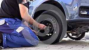 A man in work trousers replaces a car wheel,Slow Motion