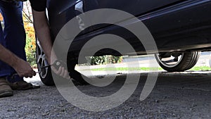 A man in work trousers replaces a car wheel,Slow Motion