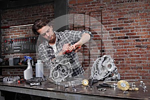 Man work with the wrench, repair and cleaning engine parts on the workbench in home garage workshop, diy concept