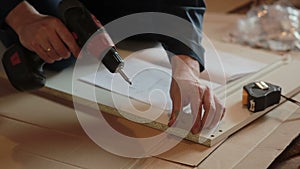 Man worker assembles furniture using instruction