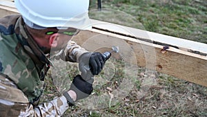 Man worker building wooden frame house on pile foundation.