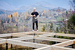 Man worker building wooden frame house on pile foundation.