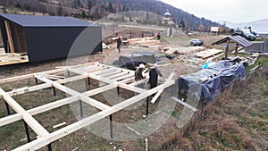 Man worker building wooden frame house on pile foundation.