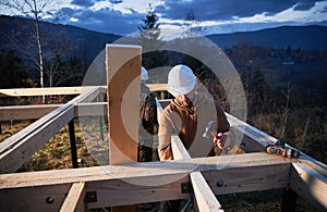 Man worker building wooden frame house on pile foundation.